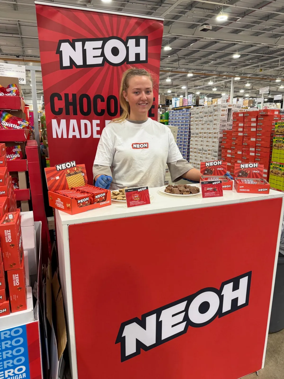 FOTS brand ambassador at a NEOH tasting stand with chocolate samples inside a wholesale club