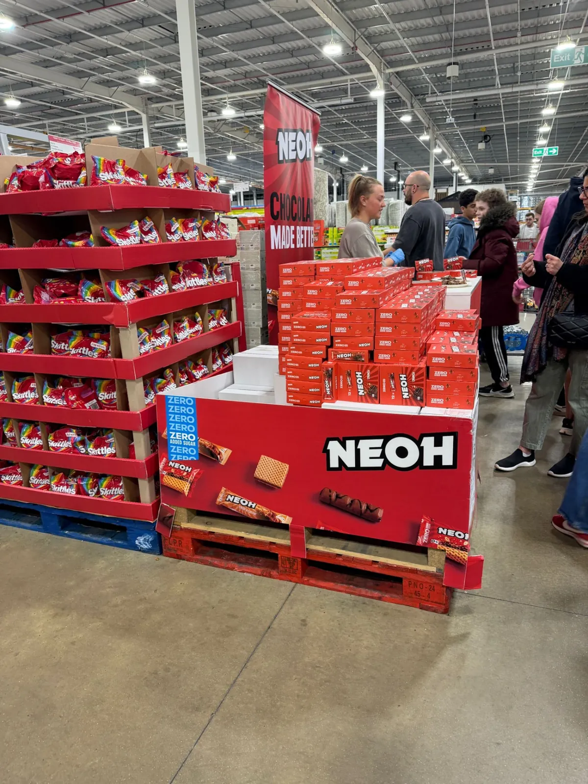 Brand Management: NEOH pallet display stacked with Zero Added Sugar packs alongside a busy tasting stand in a wholesale club