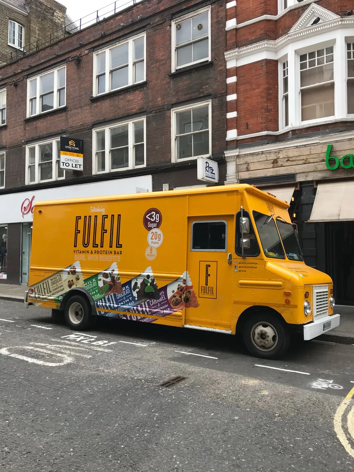 Bright yellow Fulfil Vitamin & Protein Bar branded truck parked on a London street