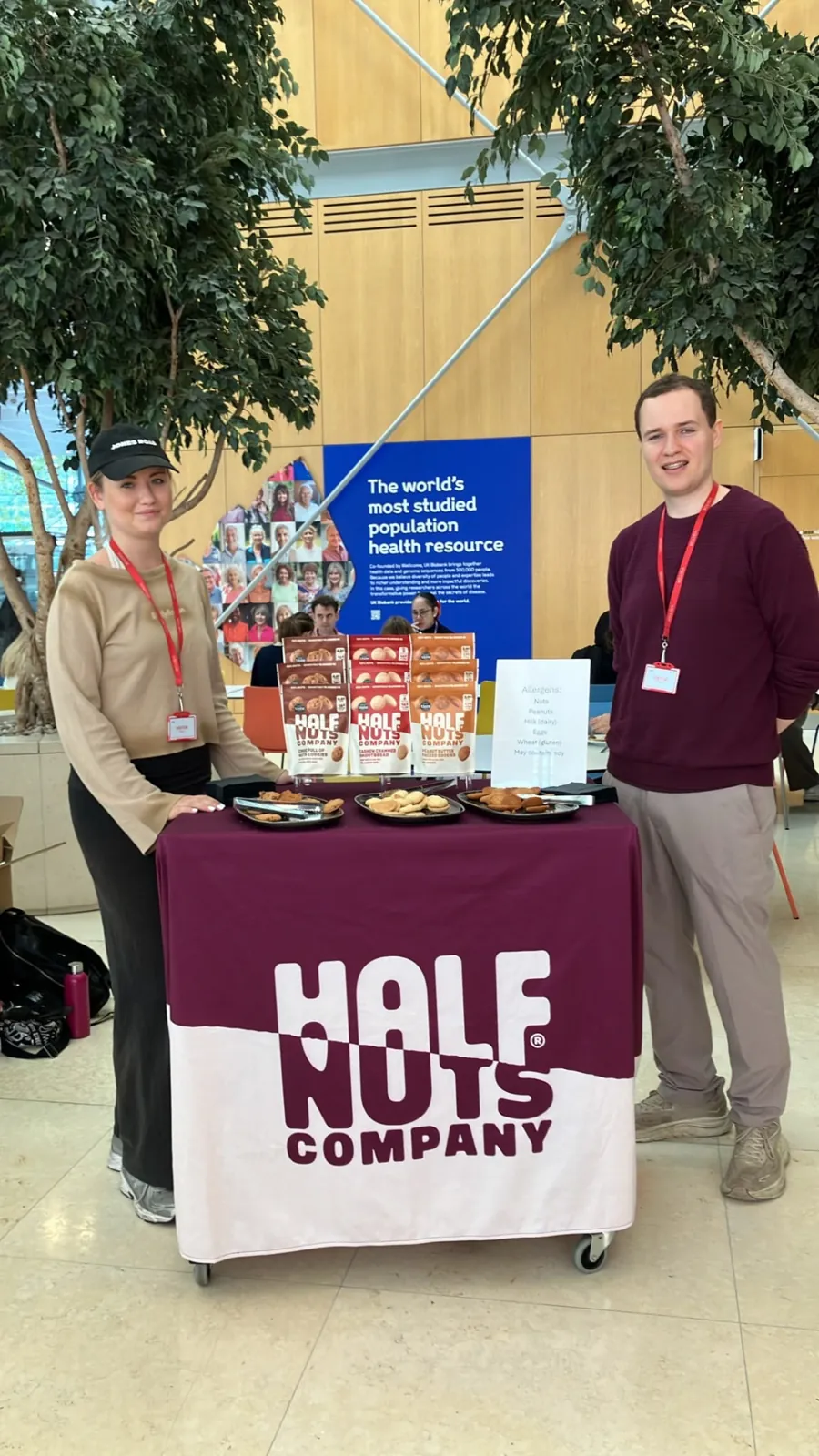 FOTS team sampling Half Nuts Company cookies from a branded stand in an office atrium